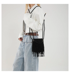 Close-up of black fringe mini crossbody bag styled on a model with white jacket