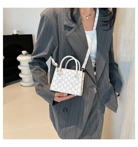 Close-up of mini white crossbody bag with grey M monogram pattern and gold hardware