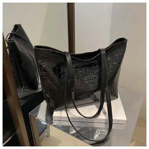 Detailed view of black crocodile pattern tote bag with glossy finish on a reflective stand