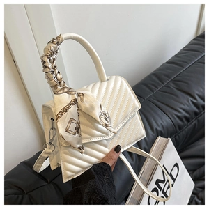 Detailed view of white quilted handbag featuring a silk scarf-wrapped handle and V-pattern