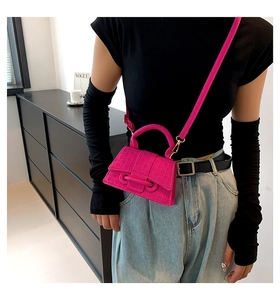 Modella che indossa una mini borsa squadrata rosa acceso testurizzata con tracolla fine