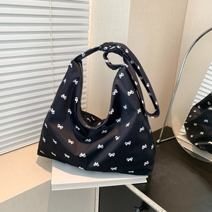 Minimalist black canvas tote bag with white bow pattern and stylish knotted shoulder strap