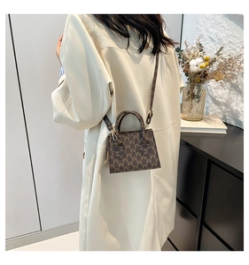 Brown monogram crossbody bag worn by model in a minimalist modern interior setting