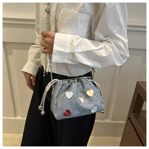 Dettaglio borsa a secchiello in denim grigio con toppe a cuore e tracolla a catena