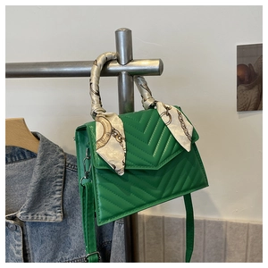 Detailed view of a green chevron quilted crossbody bag with silk scarf wrapped handle