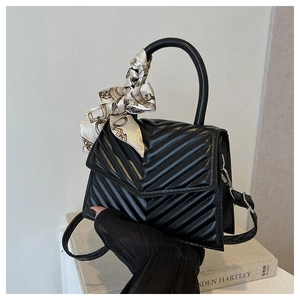 Close-up of black quilted leather handbag with a patterned silk scarf on the handle