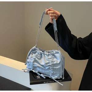 Détail du sac seau bleu clair avec plis, nœud coulissant et bandoulière en chaîne argent
