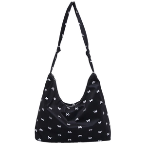 Fashionable black canvas hobo bag with white bow pattern and adjustable shoulder knot