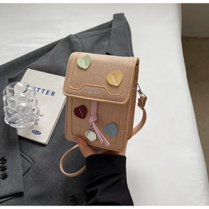 Detail of woven crossbody bag with colorful heart patches and Fashion embossed text