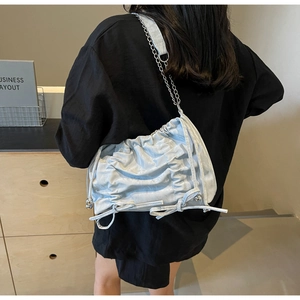 Détail du sac seau plissé bleu clair avec nœuds et bandoulière chaîne argentée pour femme