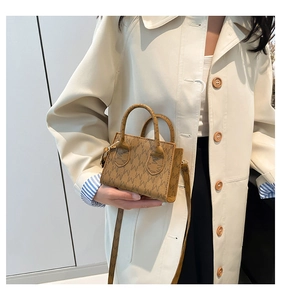 Close-up of retro brown monogram mini tote with dual handles and slim shoulder strap