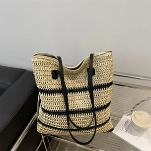 Large woven beach tote bag with black stripes and leather straps on a cafe table