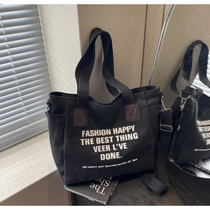 Detail of black canvas tote bag with adjustable strap and side pocket in soft window light