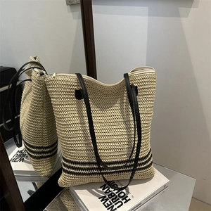 Beige woven straw tote bag with black stripes and leather straps for beach holidays