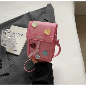 Detail of pink woven crossbody phone bag with colorful heart patches and fashion print