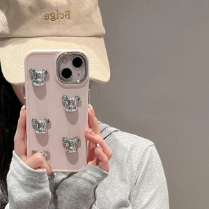 Pink matte iPhone case with silver 3D bear ornaments held by model in a mirror selfie