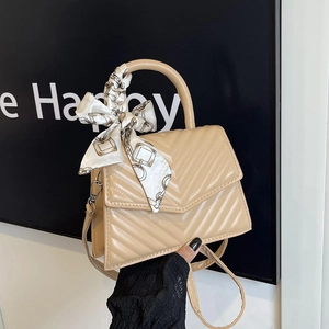 Quilted beige crossbody bag with V-shaped stitching and silk scarf on handle