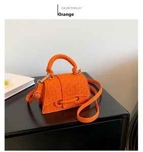 Dettaglio della mini borsa arancione a tracolla con trama intrecciata e fibbia a lucchetto