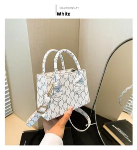 Detail of white mini tote bag with grey M-letter pattern and golden hardware accents