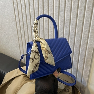 Royal blue quilted handbag with V-stitch texture and elegant silk scarf handle decoration