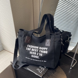 Canvas tote bag with black and white print, featuring brown leather accents and strap