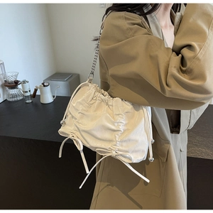 Vue détaillée du sac seau plissé blanc avec chaîne argentée et cordon de serrage