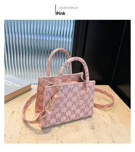Detail view of pink square tote bag with M monogram pattern and gold metal hooks