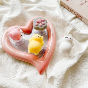 Close-up of cute cat and pig silicone phone grips on a heart-shaped ceramic plate