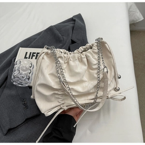 Détail du sac seau plissé blanc avec cordon de serrage et bandoulière chaîne argent