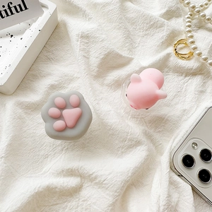 Close-up of cute silicone cat paw and pig squishy phone grip on white fabric background