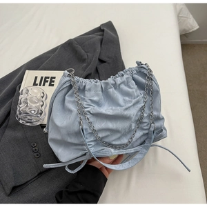 Détail du sac nuage plissé bleu clair avec chaîne argentée sur blazer gris chiné