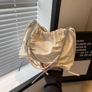 Sac seau froncé beige minimaliste avec bandoulière chaîne argentée porté à la main