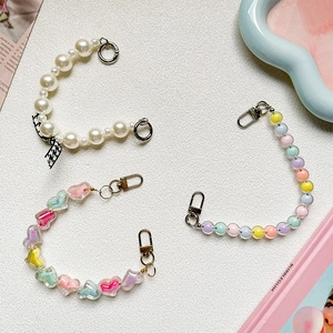 Detailed view of colorful DIY phone charms with heart beads, pearls and bow accents