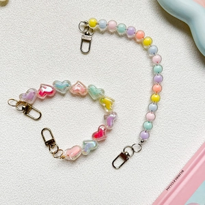 Colorful macaron beaded phone charms with heart shapes and metal lobster clasps on white surface