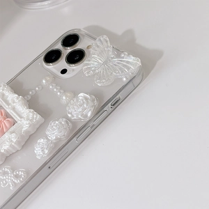 Close-up of clear iPhone case featuring 3D iridescent butterfly, roses and pearl chain