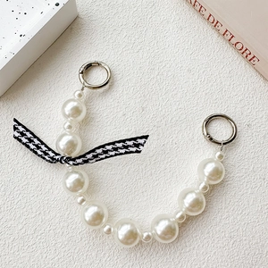Detail of pearl phone chain strap with houndstooth bow and silver metal clasps