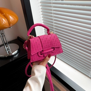 Mini borsa rosa acceso con trama intrecciata e tracolla regolabile in un ambiente lifestyle