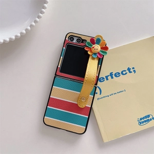 Detail of colorful striped phone case with daisy smile charm and yellow wrist strap