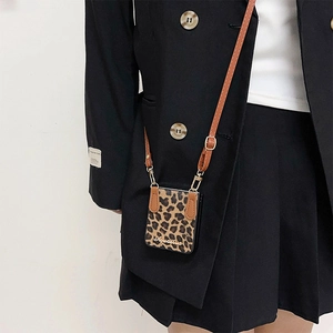 Detail of leopard print phone case with adjustable brown crossbody strap and metal clasp