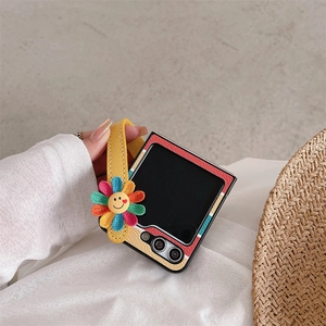 Detail of colorful striped phone case with yellow wrist strap and sunflower charm
