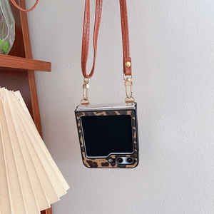 Detail of leopard print Samsung Z Flip case with brown leather crossbody strap and gold rings