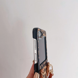 Detail view of leopard print folding case with gold hooks and brown leather strap