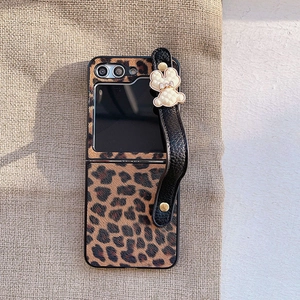 Close-up of leopard print Samsung Z Flip case with a leather hand strap and bear charm