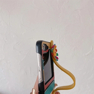 Detail of striped leather phone case for Z Flip 5 with yellow floral strap and smiley face
