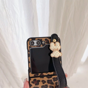 Close-up of leopard print folding phone case with wrist strap and rabbit charm detail