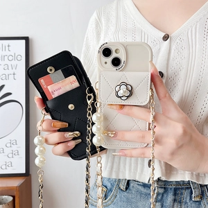 Detail of camellia flower ornament and pearl chain strap on quilted leather phone case
