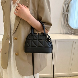 Detail of black quilted shell bag with gold double zippers and elegant top handle