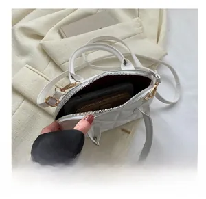 Interior view showing the capacity of white quilted shell bag with gold hardware