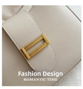 Detail of creamy white leather bag featuring a gold-toned textured metal buckle