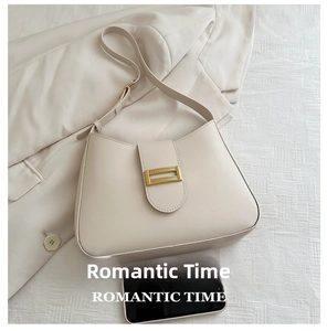 Size comparison of cream leather shoulder bag with phone on fabric background